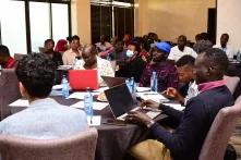 Diverse people seated around tables with laptops