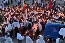 Crowd of mourners holding candles in the street at dusk