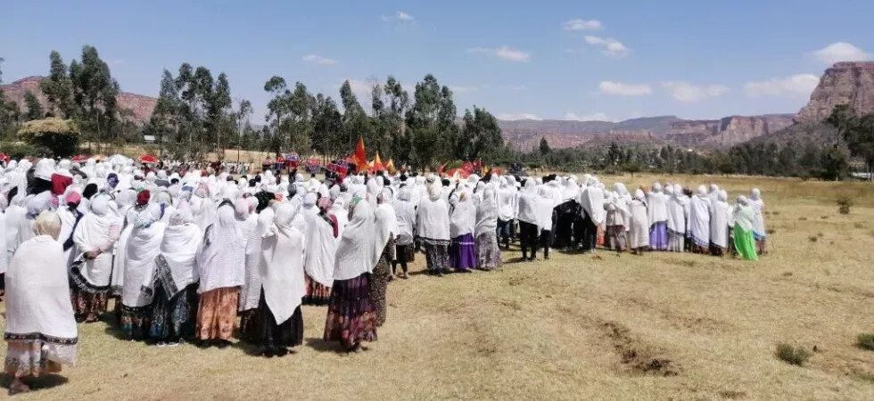 Women in traditional dress gathered in an open field