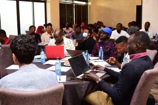 Diverse people seated around tables with laptops