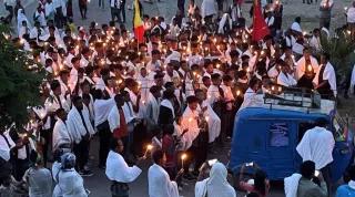 Crowd of mourners holding candles in the street at dusk